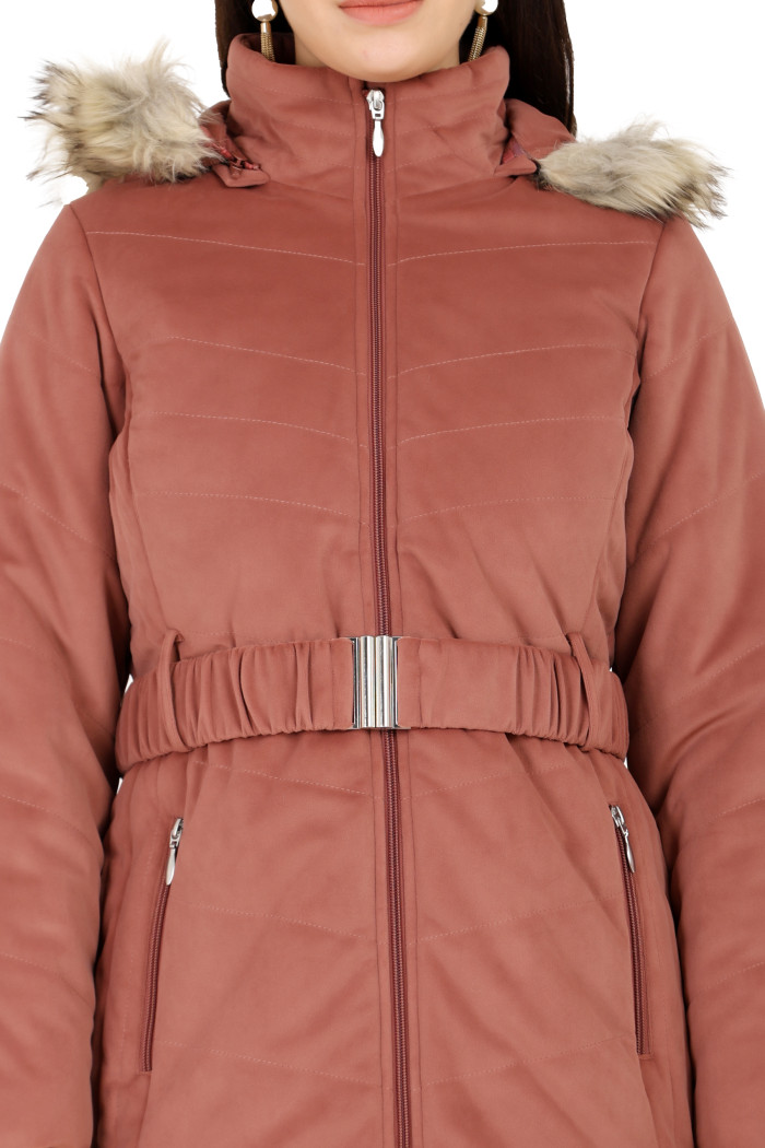 A cropped view of a woman in Coatsnmore’s onion pink velvet quilted jacket, featuring a mandarin collar, removable hood, adjustable waistband zip closure, and concealed zippered side pockets.